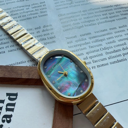 Reloj de mujer con correa de acero y perforaciones puntuales con superficie de concha de disco ovalado